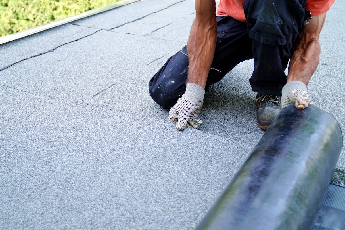 worker installing tar foil on the rooftop of building. Flat roof installation. Waterproof system by gas and fire torching. Roofing felt. Roofer working. Roofer working tool. Waterproofing