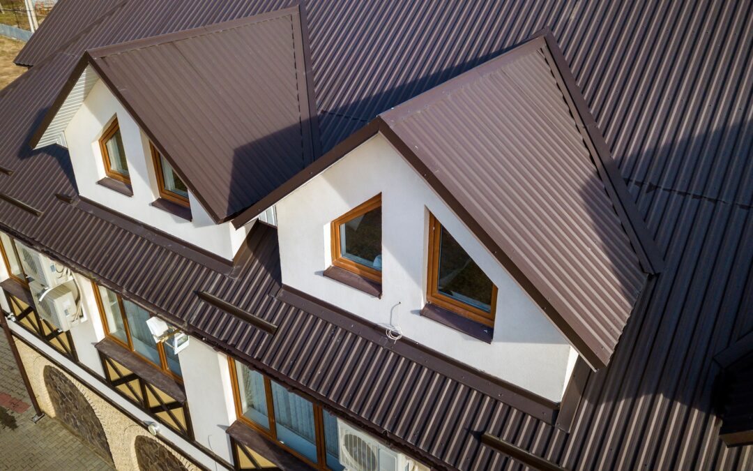 Close-up aerial view of building attic rooms exterior on metal shingle roof, stucco walls and plastic windows.
