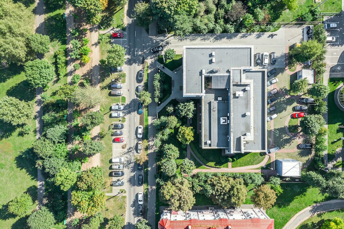 aerial top view of a small business building among green trees in residential area