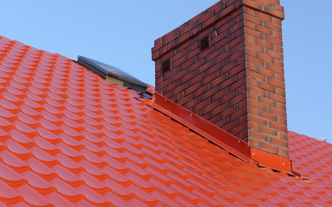 Closeup of red roof metal covering with brick-made chimney
