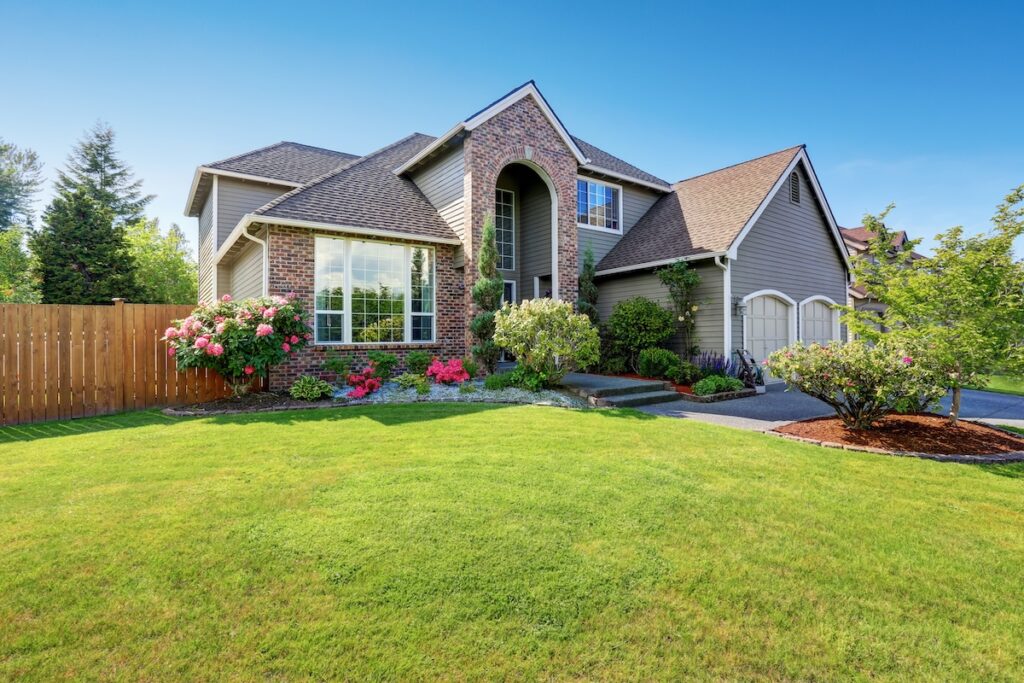 Luxury house exterior with brick and siding trim and double garage. Well kept garden around. Northwest, USA