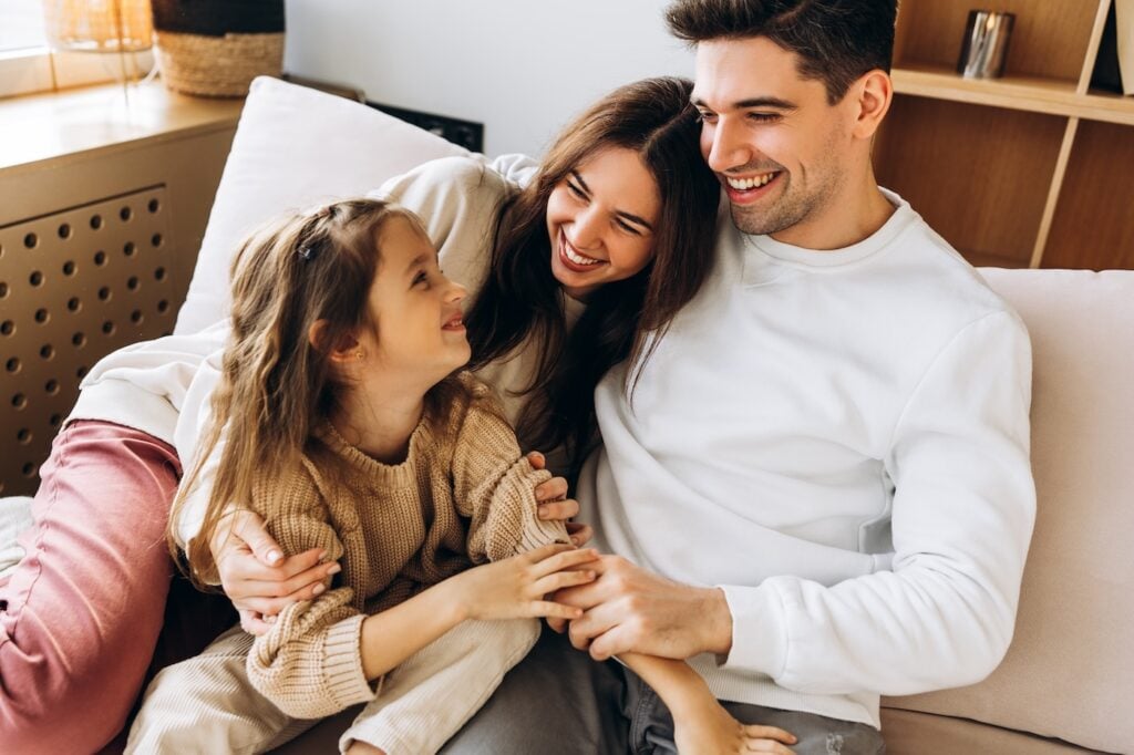 Parents and daughter enjoying quality time together, creating a heartwarming scene of family bonding and happiness in their cozy living room