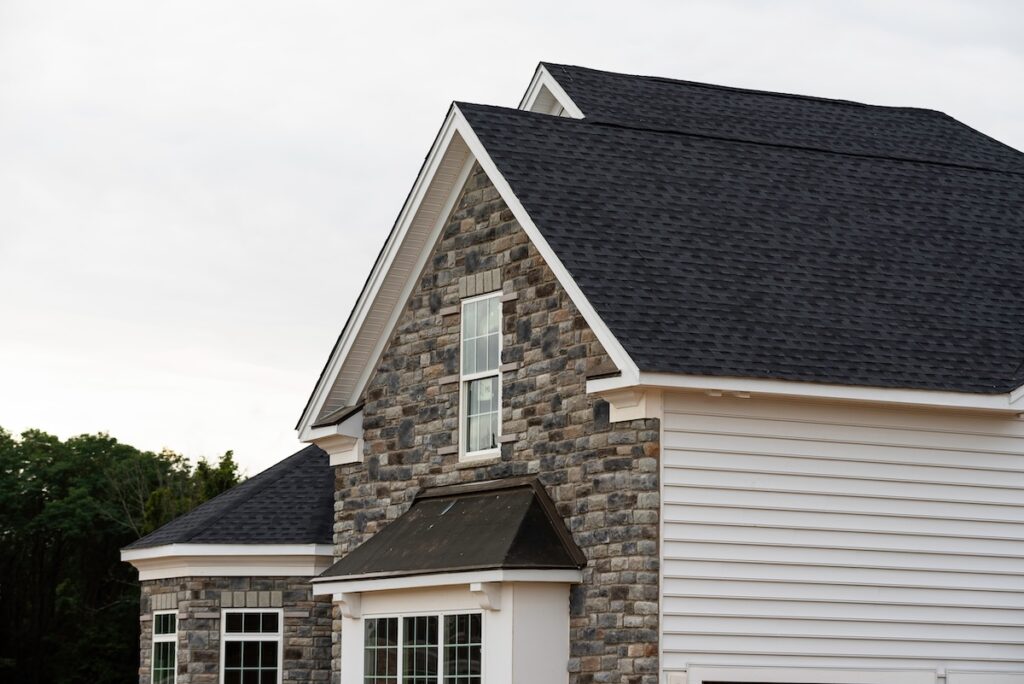 edge of roof shingles on top of the house dark asphalt tiles on the roof background