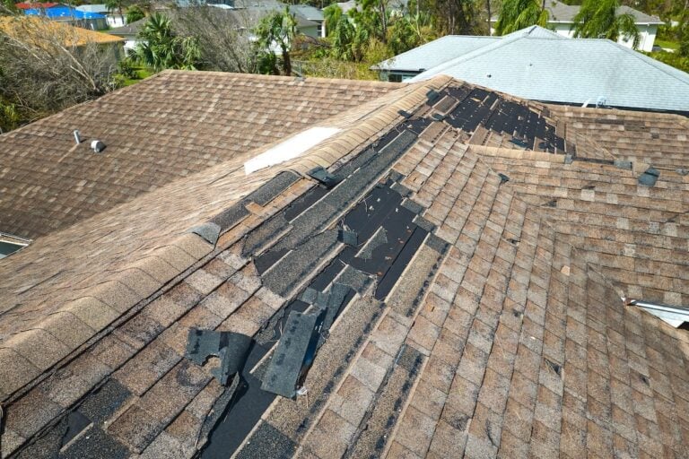 Damaged house roof with missing shingles after hurricane Ian in Florida. Consequences of natural disaster.