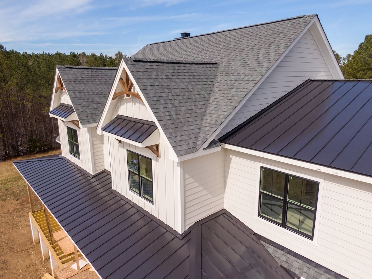 Sunny Daytime Drone Images of a Custom Home in the Final Stages of Construction. It Features a Roof With Architectural Asphalt Shingles and Standing Seam Accents.