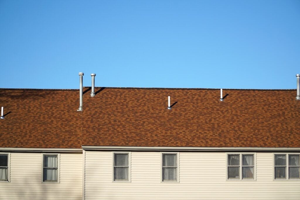 certainteed vs gaf close up on old apartment building with red shingle roof