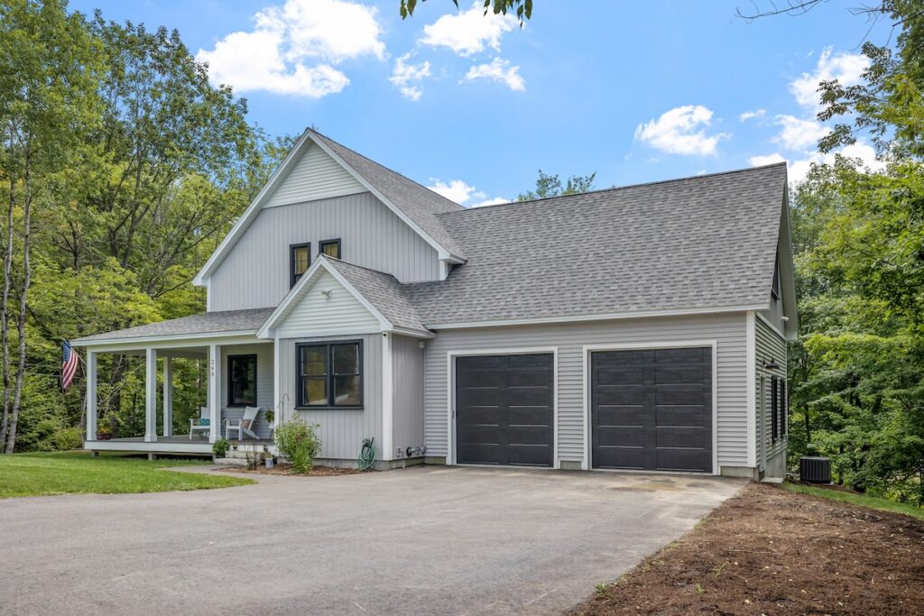 certainteed landmark shingles Modern custom new England colonial home with an American flag on a sunny day