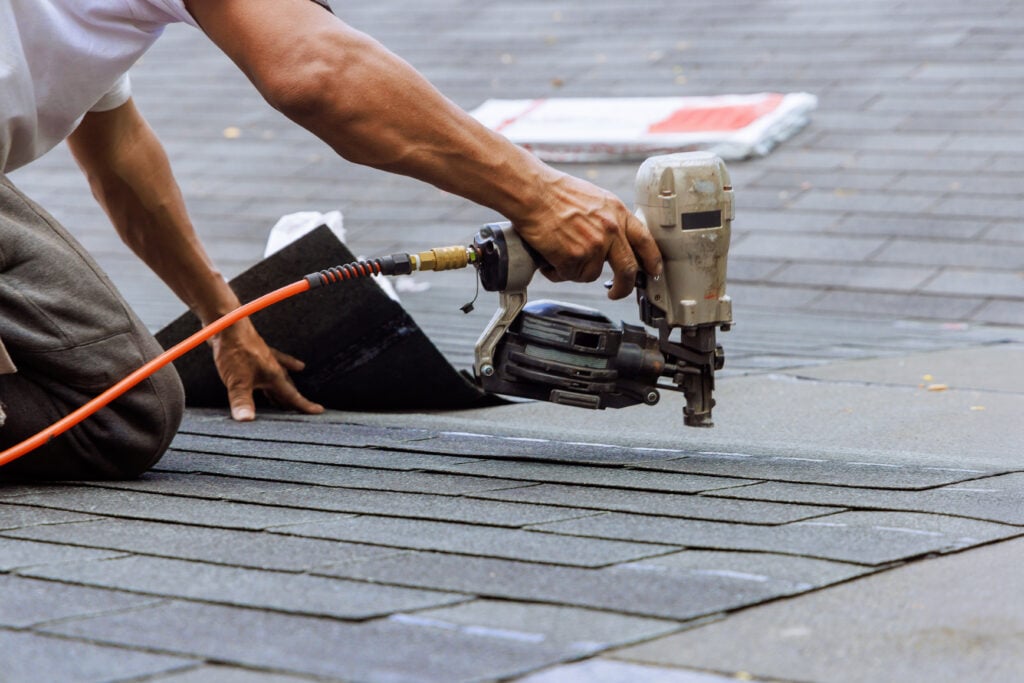roofing tools Air pneumatic nail gun used by roofer to install new asphalt bitumen shingles