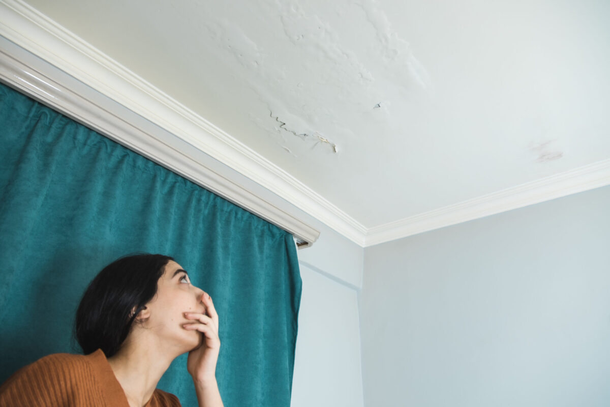 damaged ceiling with sad woman in home