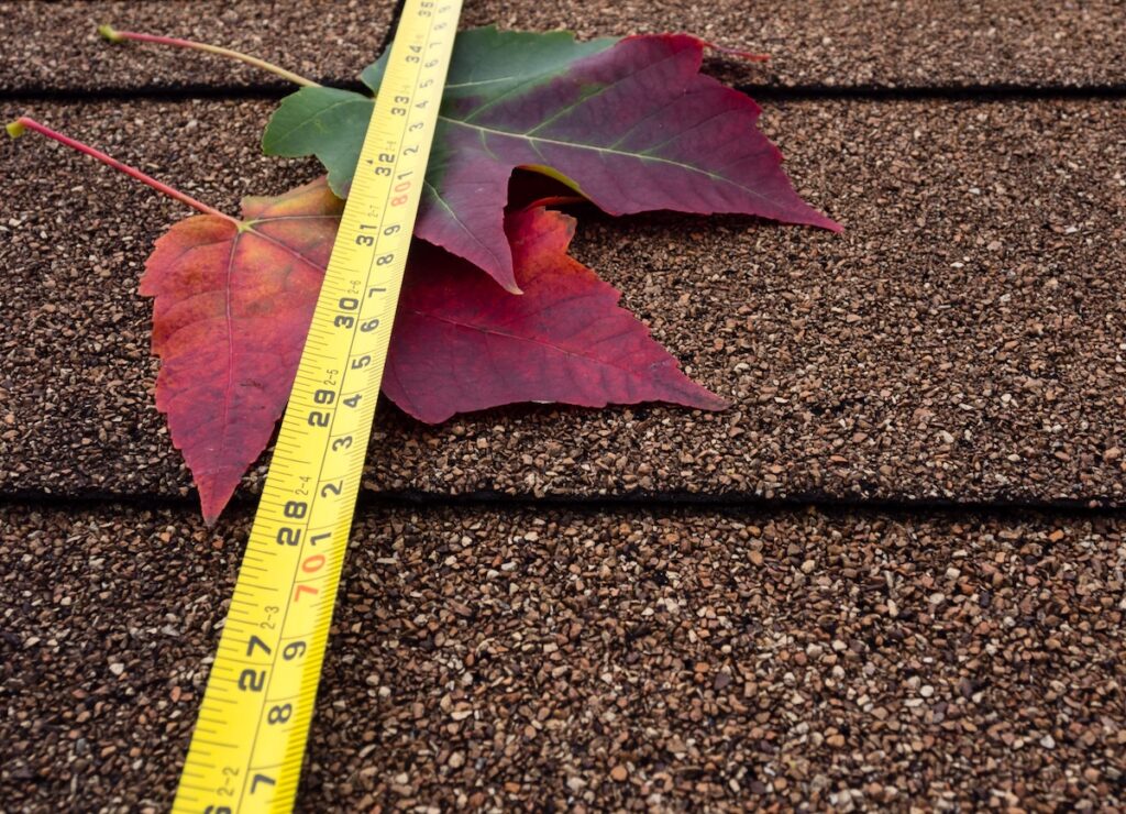 how to measure a roof for shingles Tape measure and autumn leaves on asphalt shingles