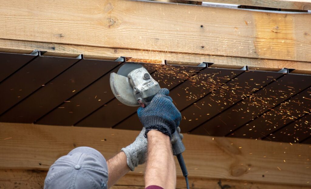 soffit repair worker grey cap with electric saw repairing wooden roof