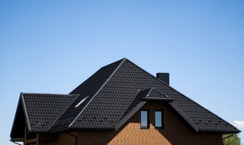 Brown corrugated metal profile roof installed on a modern house with a attic windows