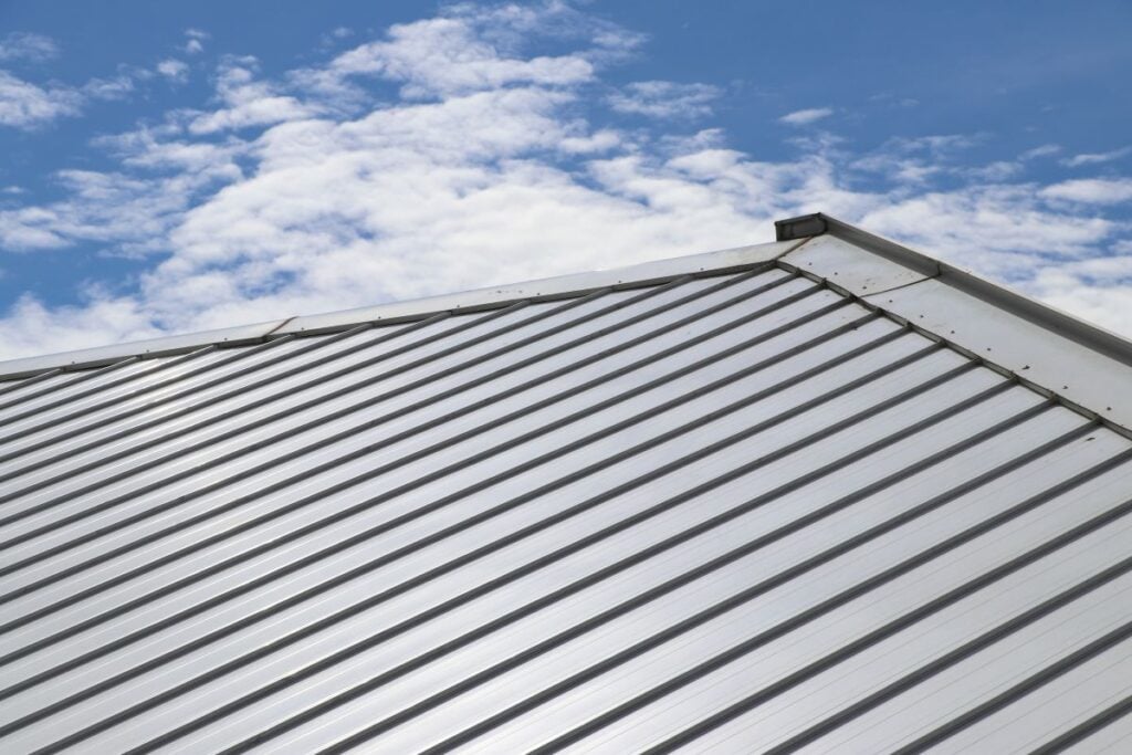pvdf coating close-up view of a metal sheet roof with parallel ridges, featuring a durable PVDF coating, set against a blue sky with scattered white clouds.