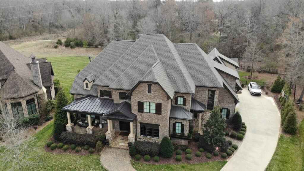 asphalt roof repair asphalt roof repair Large two-story brick house with multiple roof gables and a front porch. A curved driveway leads to a white car near the garage. With leafless trees nearby, the property may benefit from regular roof repair to prevent common issues.