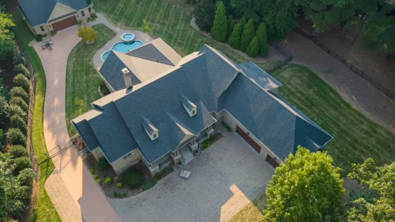 Aerial view of a large house with a gray roof, circular driveway, landscaped yard, and a backyard pool—perfect for your next roof replacement Mooresville NC project.