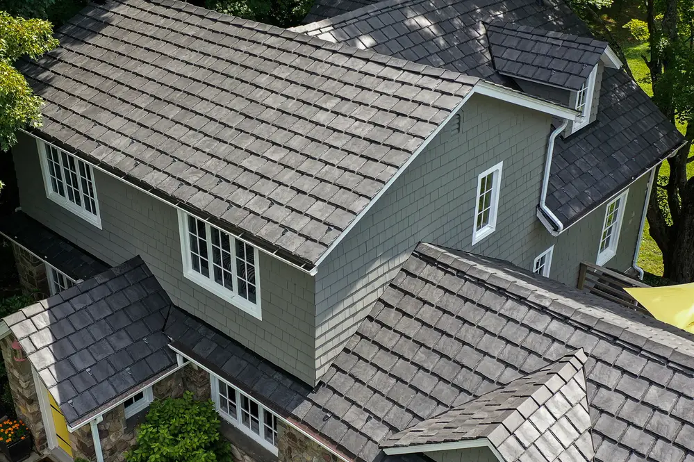 Aerial view of a house with multiple pitched roofs covered in Brava Composite Roofing’s dark gray shingles, surrounded by trees and greenery in South Carolina.