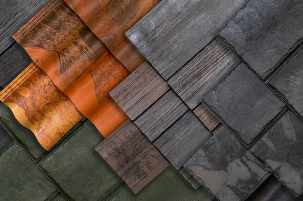 A variety of Brava Composite Roofing tiles in different colors and textures, including green, orange, brown, and gray, arranged in diagonal rows. Perfect for homes in South Carolina or North Carolina.