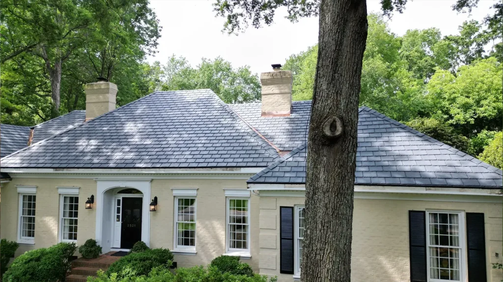 A one-story brick house with a new composite slate roof, set in a wooded lot.