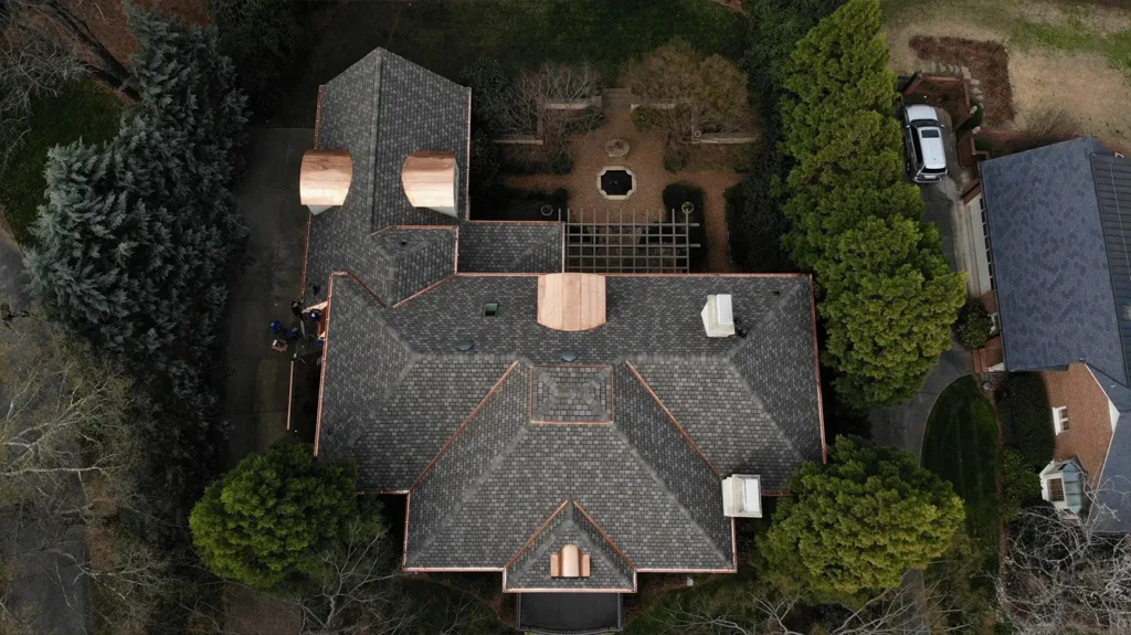 Aerial view of a Highland slate roof with copper flashing and gutters on a large house surrounded by trees.