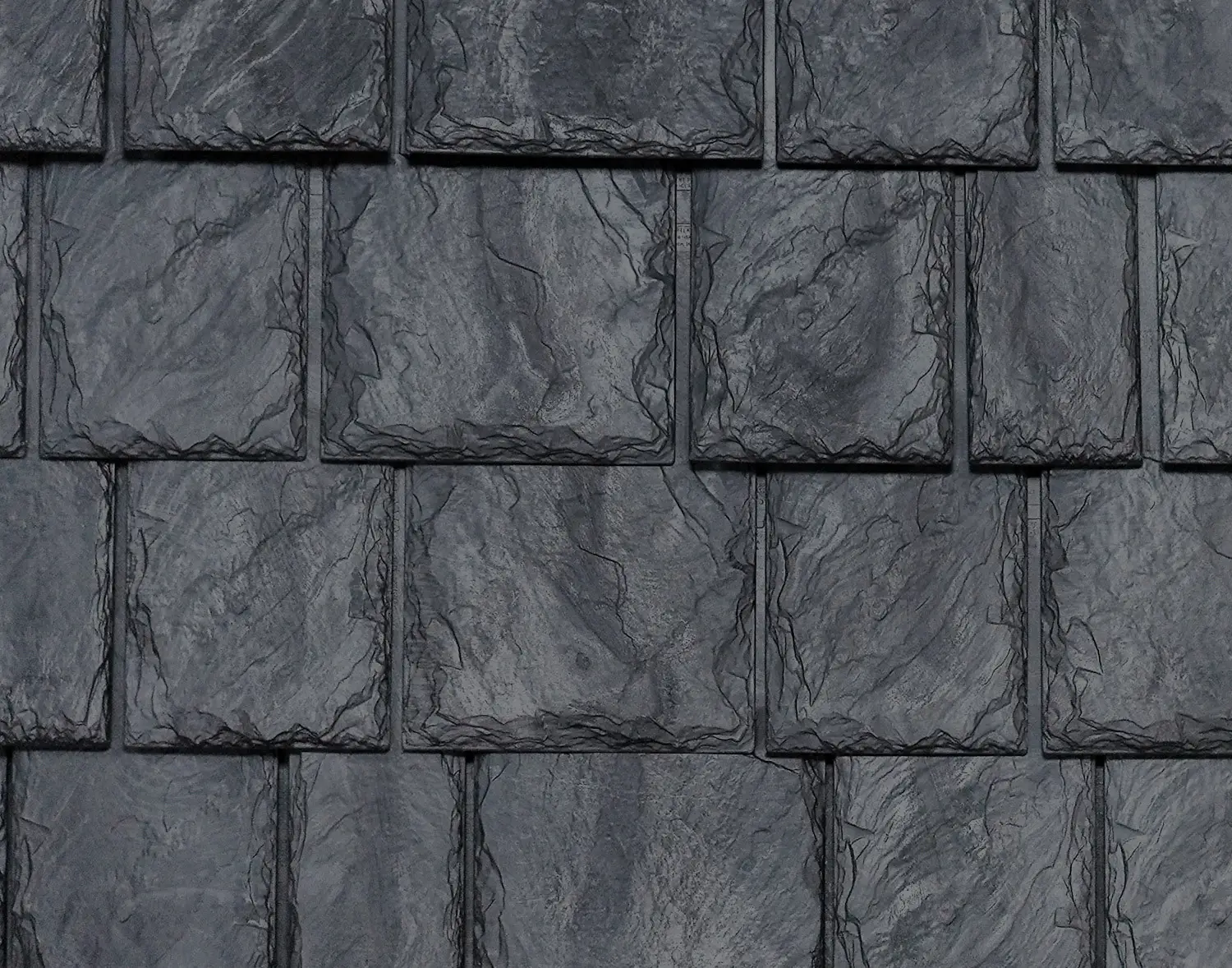 Dark gray rectangular Brava composite roofing shingles with a rough, textured surface.